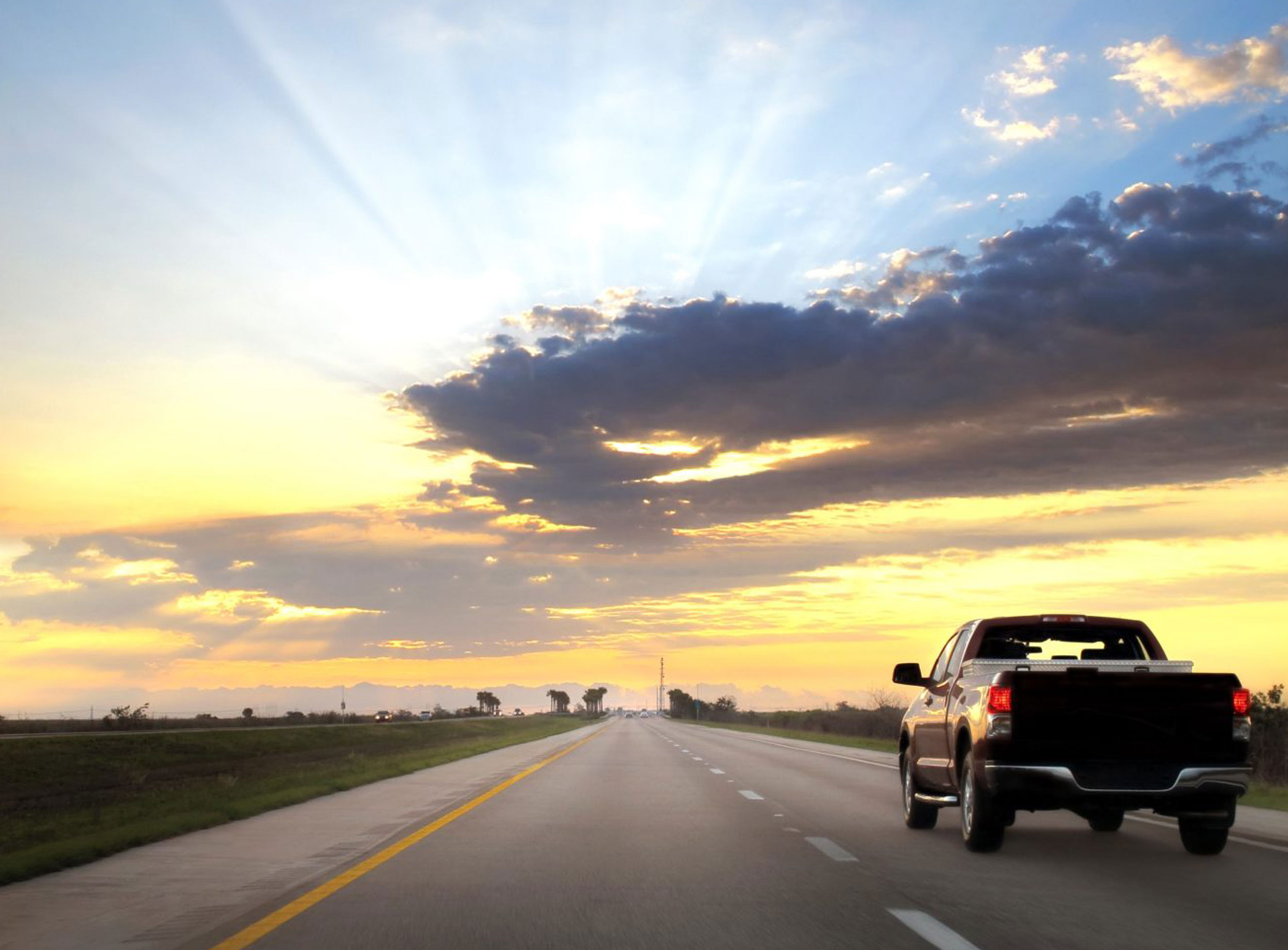 image of truck driving on road into sunset