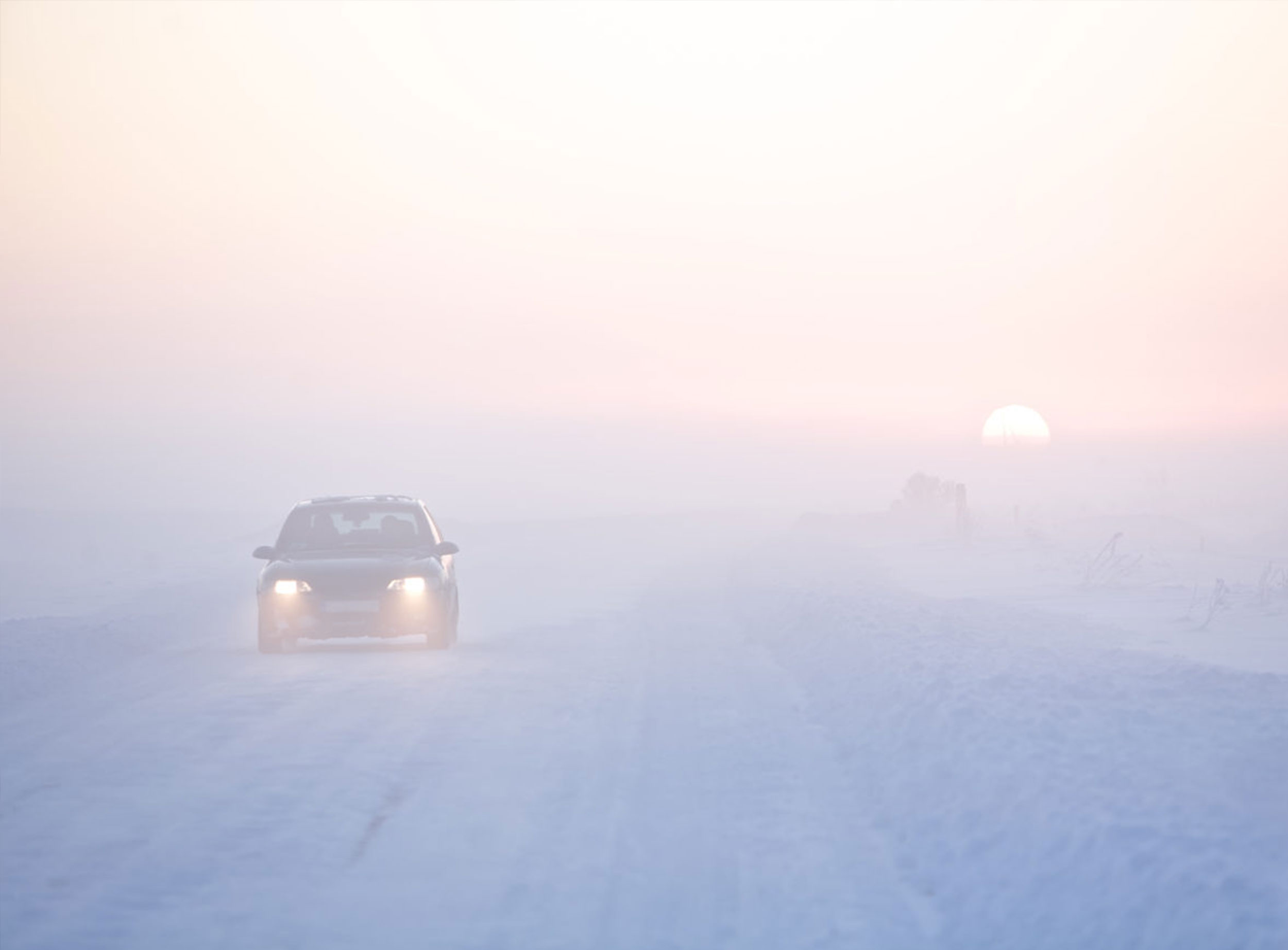 image of car on snow-covered road at sunrise
